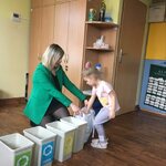 dziecko wyjmuje  odpady do segregacji z woreczka trzymanego przez kobietę.