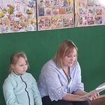 kobieta czyta dzieciom książkę obok siedzi dziewczynka