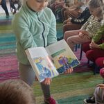 dziewczynka pokazuje dzieciom ilustrację w książce