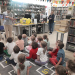 Bibliotekarka pokazuje dzieciom książkę o zwierzętach.