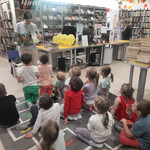 Bibliotekarka pokazuje dzieciom książkę o dinozaurach.