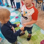 Dwójka dzieci łączy rozcięte kółko na pół w całość_ w tle inne dzieci