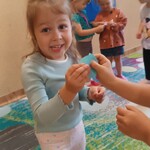uśmiechnięta dziewczynka łączy rozcięte kółko _ z tyłu też dzieci