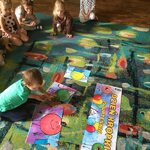 dziecko układa  papierowe puzzle na dywanie