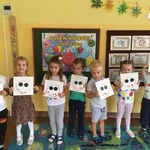 dzieci stoją w rzędzie i pokazują swoje prace