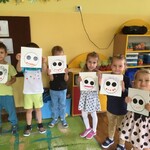 kilkoro dzieci stoi w rzędzie i pokazuje swoje prace