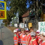Przedszkolaki stoją przy ulicy i przyglądają się znakom drogowym