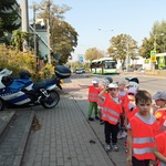 Dzieci idą chodnikiem i oglądają mijany motocykl