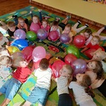 Dzieci leżą na dywanie trzymając balony