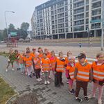 Grupa dzieci ustawionych parami stoi w pobliżu przejścia dla pieszych