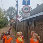 Kilkoro dzieci stoi na chodniku_ dziewczynka ręką wskazuje na znaki drogowe