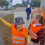Dzieci stoją w pobliżu skrzyżowania z sygnalizacją dla pieszych_ chłopiec włącza przycisk