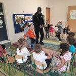 Pan policjant pokazuje dzieciom_ że na zielonym świetle można przejść