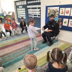 Pan policjant rozdaje dzieciom upominki - opaski odblaskowe