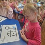 Dziewczynka obserwuje poruszanie się ozobota na jej kartce z zaznaczonymi kodami