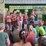 Piątka dzieci pokazuje obrazki kolegom siedzącym na dywanie