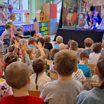 Aktor trzyma pacynkę_ dzieci siedzą naprzeciwko i klaszczą