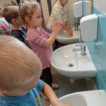 Dzieci stoją przy zlewach i myją ręce.