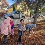 Dwoje dzieci grabi liście_ dziewczynka na pierwszym planie stoi_ trzymając grabie.