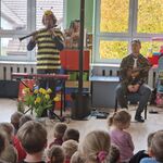 Pan w przebraniu trzmiela stoi trzymając klarnet_ obok na krześle siedzi pan ze skrzypcami