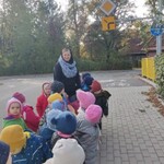 grupa dzieci ogląda znak drogowy_ droga z pierwszeństwem_ na końcu stoi pani