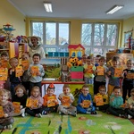 Grupa dzieci pozuje z pszczelarką trzymając dyplomy.