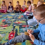 Dzieci siedzą na dywanie trzymają w rękach węzę.