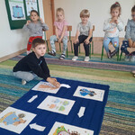 Chłopiec układa strzałki wskazujące następstwo pór roku.