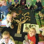 dzieci siedza wokół drzewa ułożonego z klocków_ lisci i kasztanów.