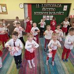 Dzieci stoją w 3 szeregach_ w rękach trzymają pompony i kręcą nimi (młynki).