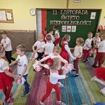 Dzieci w biało - czerwonych ubraniach tańczą w parach lub trójkach.