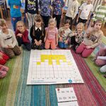 Grupa dzieci znajduje się przed matą_ na której ułożona jest żółta korona.