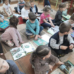 Dzieci oglądają książki rozdane przez panią bibliotekarkę.