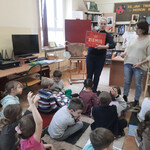 Pani bibliotekarka pokazuje dzieciom książkę pt. _Pod ziemią_.