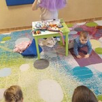 pani siedzi przy stoliku_ trzyma tiulową spódniczkę_ obok dziecko.