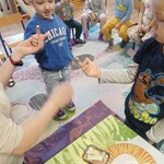 dzieci siedzą na krzesełkach_ dwóch chłopców stoi _ na palcu mają naparstek.