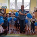 Dzieci i pani stoją z balonami w ręku.