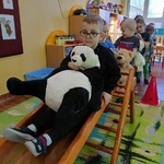 Przedszkolak pokonuje zjeżdżalnię z misiem panda.