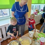Dziewczynka przekłada pokrojone jabłka do miski z ciastem.