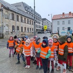 Grupa dzieci stoi przy skrzyżowaniu ulic.