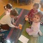 Grupa dzieci układa puzzle na dywanie.