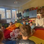 Dzieci bawią się chustą z misiami.