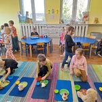 Dzieci w różnych miejscach w sali_ na dywanie_ przy stolikach. na dywanie misie.
