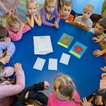 dzieci przykucnęły wokół stolika_ na środku leżą kartki świąteczne i koperta.