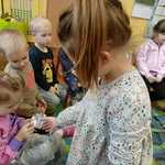 Dziewczynka pokazuje kolegom siedzącym na krzesełkach tabletki.