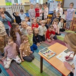 Dzieci siedzą_ stoją na dywanie_ autorka podpisuje swoją książkę.