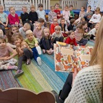 Nauczycielka trzyma otwartą książkę_ dzieci patrzą na nią.