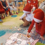 dzieci pochylone nad papierowym worku z namalowanymi kształtami_ dopasowują elementy.