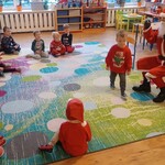grupa dzieci siedzi na dywanie_ Św. Mikołaj siedzi naprzeciwko na krześle.