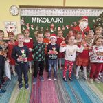 Grupa dzieci stoi w towarzystwie Mikołaja.